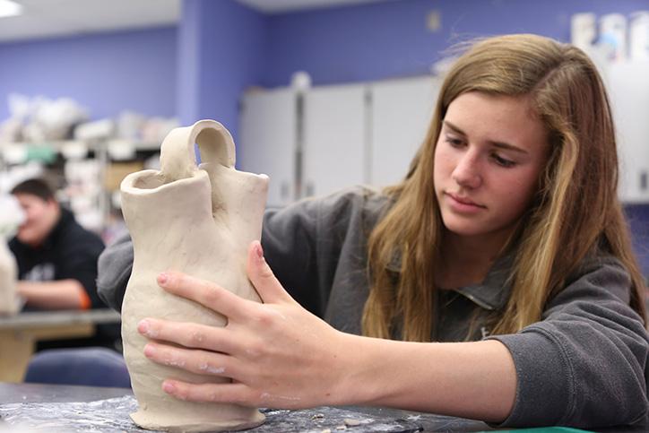 Ceramics/Pottery 1 student, freshman Julia Plescha shapes and smooths her Native American wedding vase. Plescha made the base of her vase using a pottery wheel before creating the upper part via coils. 