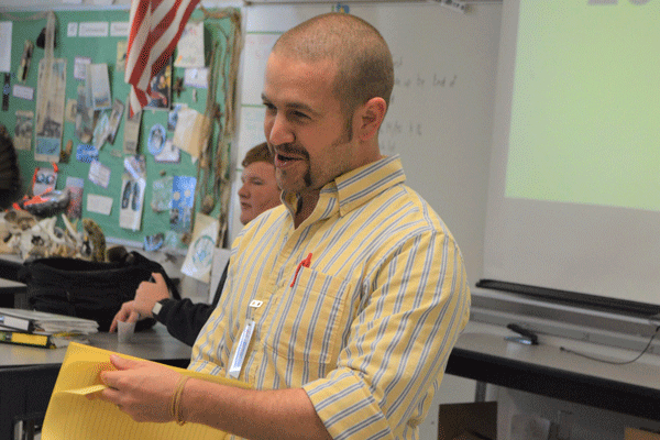 Science teacher Marc Pooler passes out FRQs during sixth period. Pooler, one of 24 teachers who took part in the Dare Week fundraiser, agreed to shave his beard to raise money. He shaved in stages, one stage being Tuesday’s handlebar mustache.