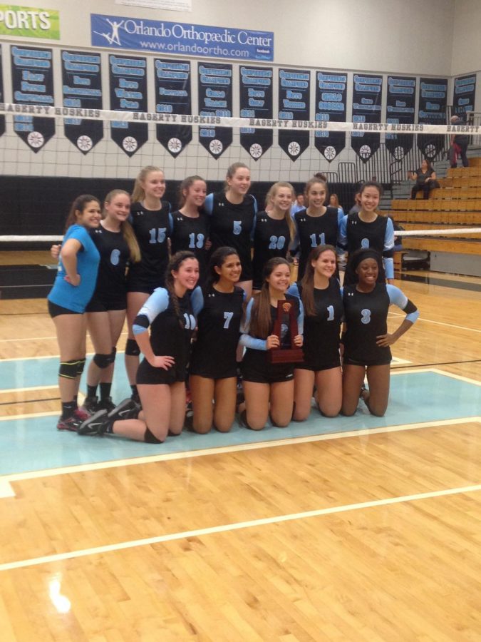 The+girls+volleyball+team+holds+the+district+championship+trophy.+The+team+defeated+Harmony+3-0+to+earn+it.