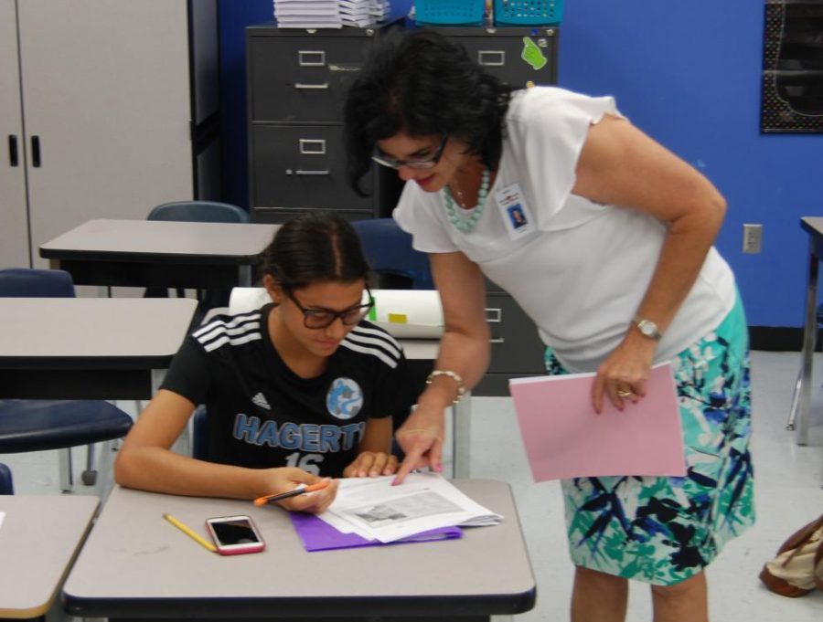 Junior Claudia Montes works on spanish assignment with spanish teacher Nitza Ariza. Montes has adapted to the change by joining clubs such as Key Club. 