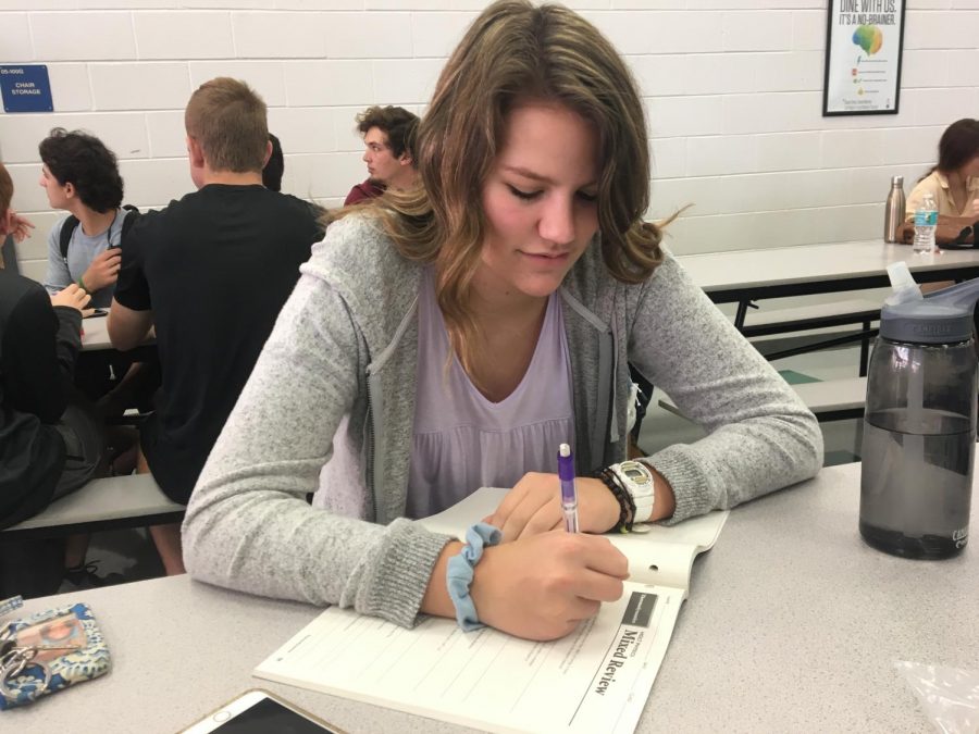 Junior Olivia Ott works on her Physics homework that she was assigned the period before during lunch. She planned to work ahead on her assignment because she has multiple other assignments to do and lacrosse practice after school.