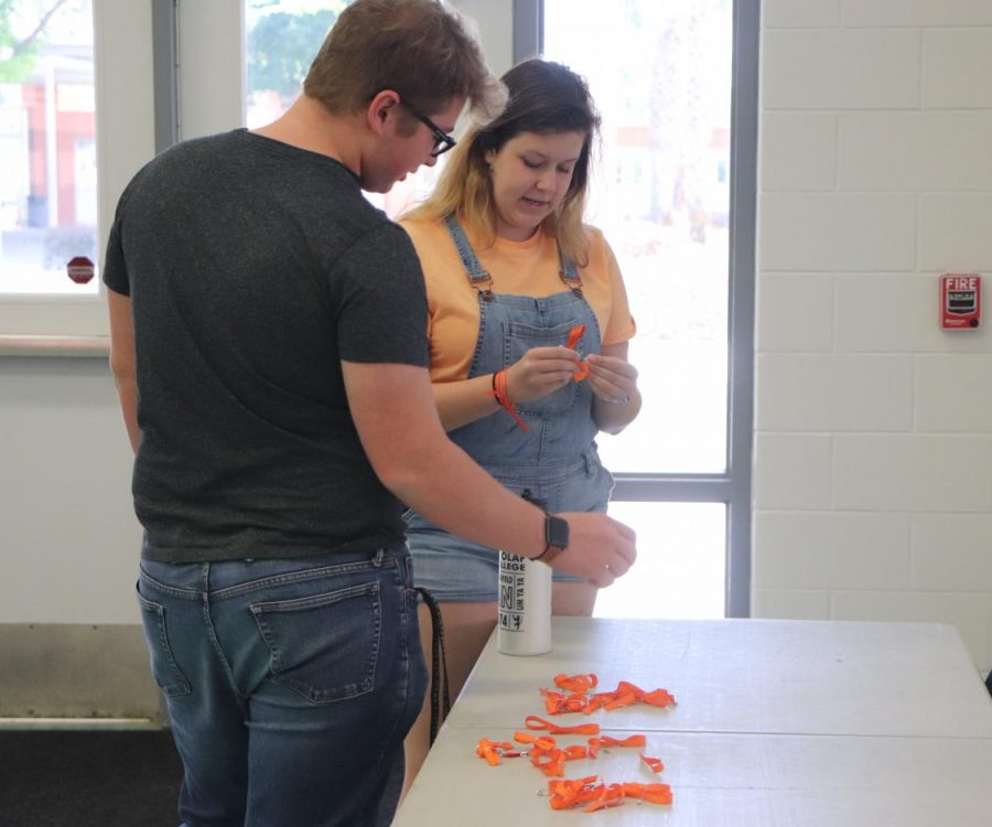 Senior Camryn Willett passes out orange ribbons during lunch. Willett, along with senior Courtney Ring and juniors Avery Watson and Valeria Rivera made the ribbons themselves and passed them out every Wednesday. 