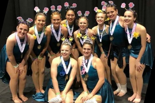 The winterguard team smiles and celebrates with their bronze medals. They broke the previous school record by placing third at the FFCC Championships.