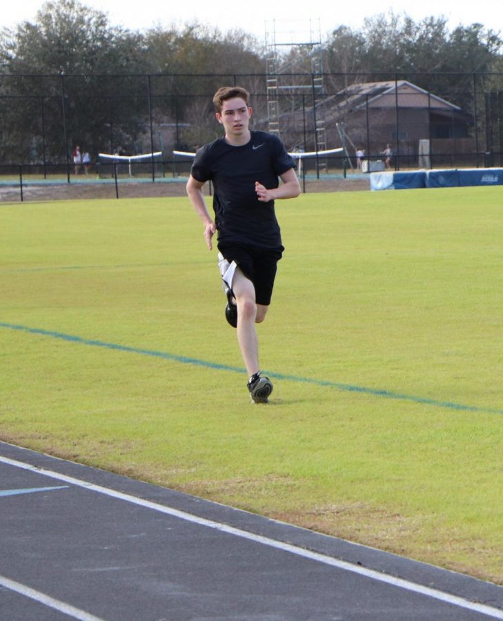 Track runner Thomas Welsh runs on the grass during track practice last year to avoid injury since the grass is not as hard as the asphalt track. The team hopes to raise enough money to get a rubber track by winter break.