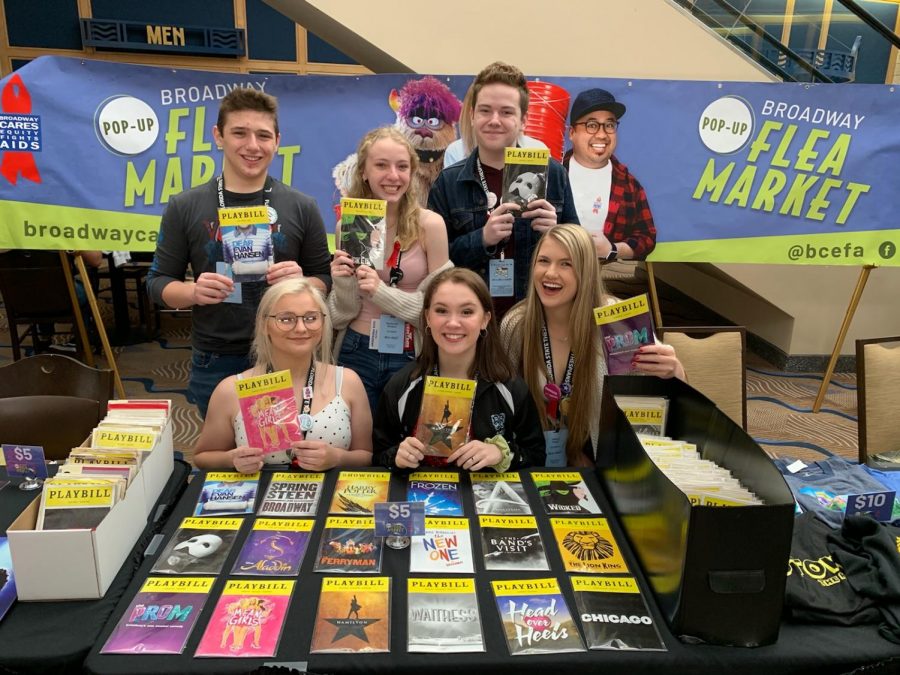 Troupe members take picture with famous musical playbills. 