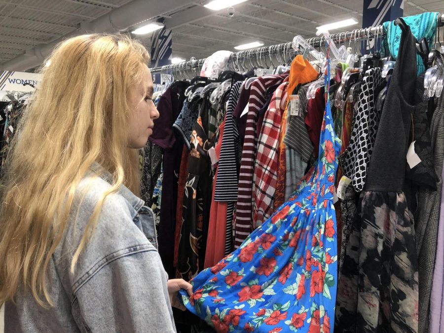 Junior Sarah Rifenberg browses through dresses at Goodwill. Many students visited similar thrift shops for cheap, trendy outfits.