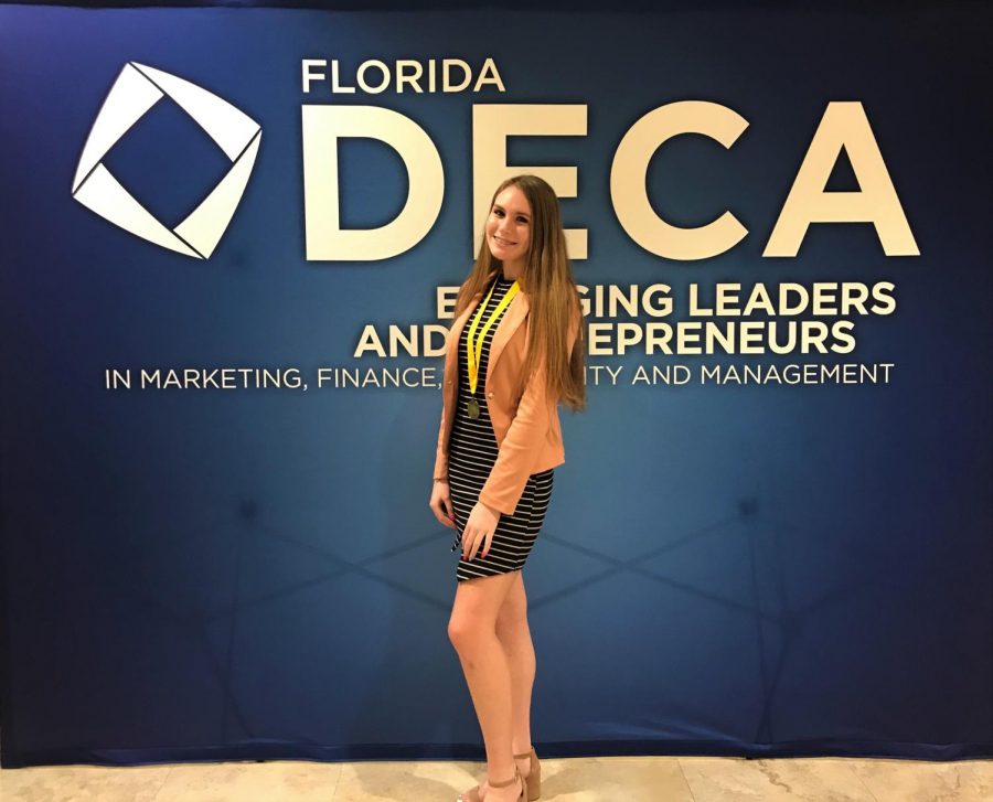 Junior+and+DECA+president+Laura+Darty+poses+for+a+picture+after+receiving+a+first+place+medal+for+presentation+in+her+category.