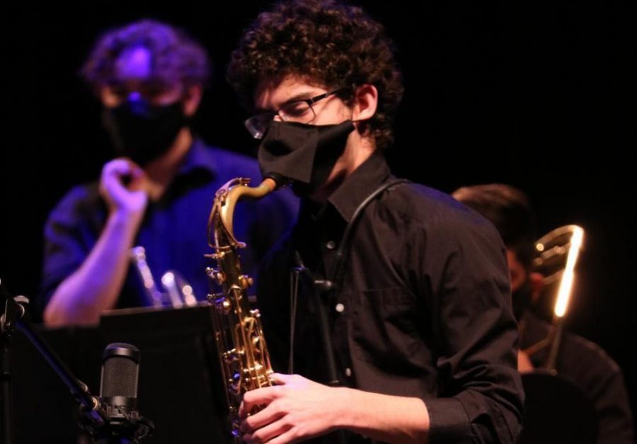 Junior Victor Acuna plays the saxophone during a virtual concert. Students have coverings over their instruments and wear special masks when playing them. 