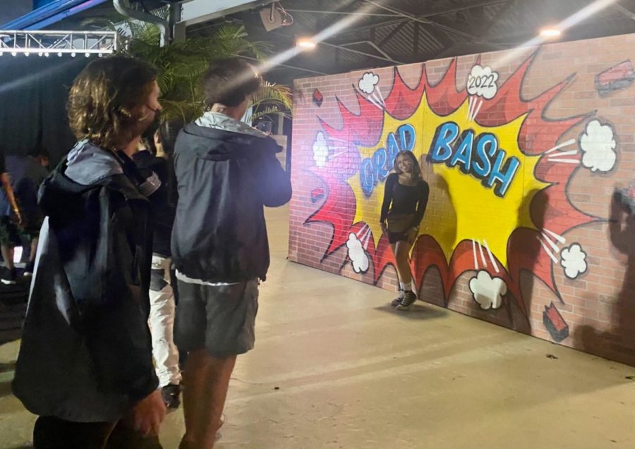 Students taking photos in front of a Universal Grad Bash mural. Students were able to travel through both parks to enjoy food, rides and street entertainment. 