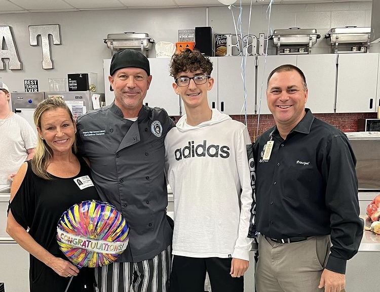 Thompson+poses+with+his+family+and+Frasca.+They+came+in+to+surprise+him+with+balloons+and+flowers+during+his+Culinary+4+class.+