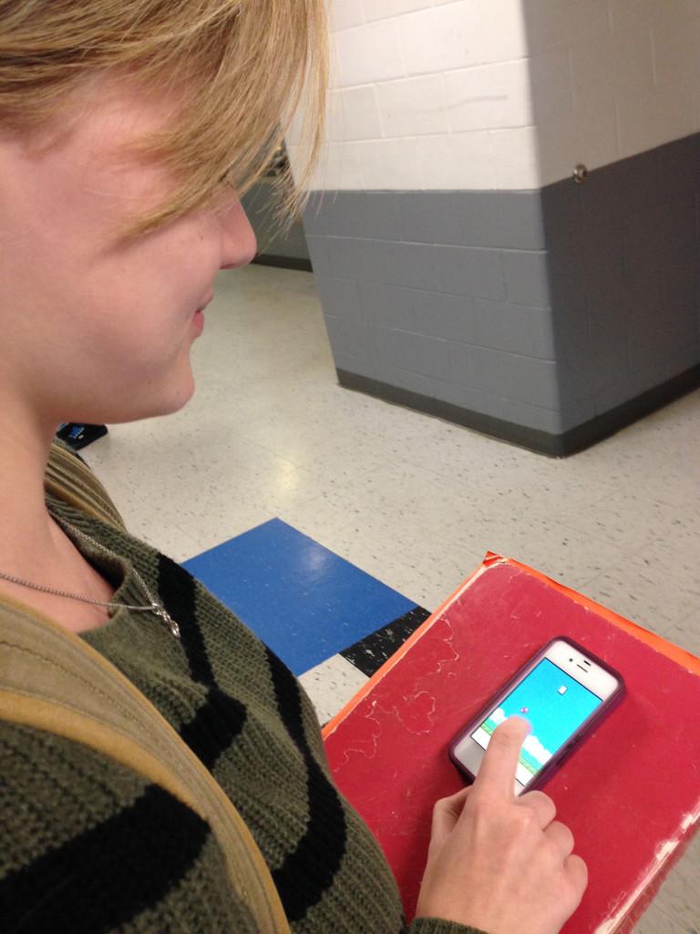 Junior Kay Hammack begins playing Flappy Bird in the hallway during break.  Many students used whatever time they had to play Flappy Bird, including during break, between classes, at lunch and in the bathroom.