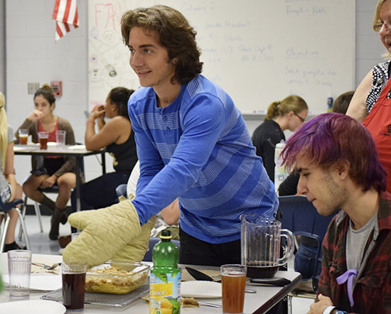 Junior Trey Hogan takes a freshly baked apple crisp to his table to serve his peers.