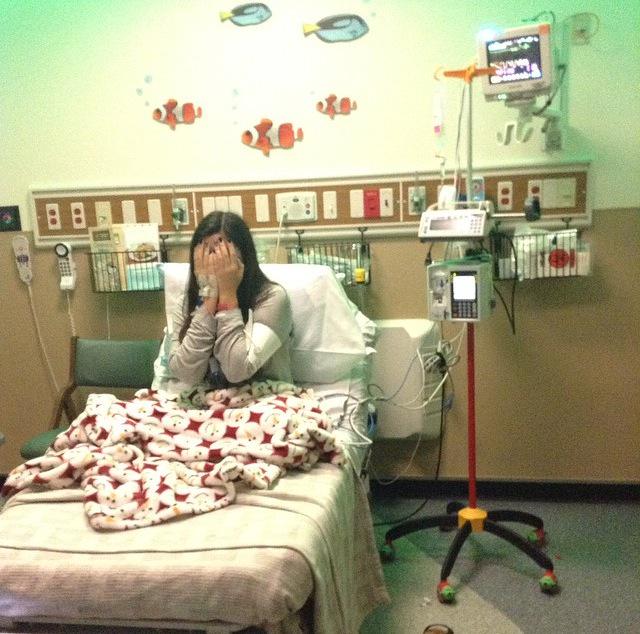 Junior Kim Ariza laughs at her younger sisters attempts to cheer her up while receiving chemo.   Arizas first day of chemotherapy was spent with her family and friend Hannah Suehle.