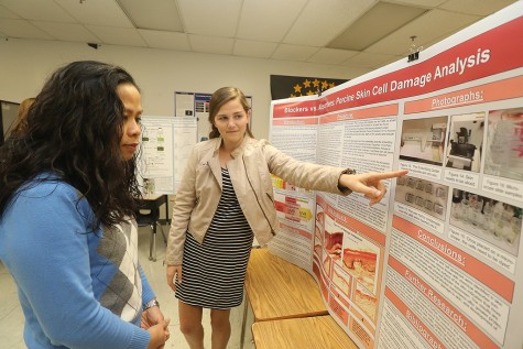 Freshman Reagan Pomp presents her project to media specialist Po Dickinson. Pomp studied the differences in chemical and physical sunscreens by testing their efficiencies on pigskin. She is one of the six girls in the experimental science class, and says the support system of women in STEM has inspired her to continue pursuing science. 