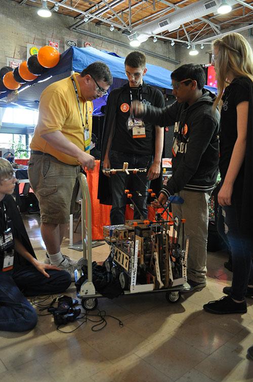 Members of the Mechromancers tend to their robot while a judge observes.