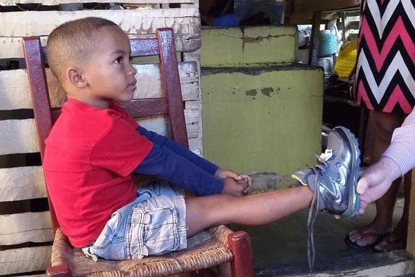 A young boy is fitted for shoes in 2016.  Junior Xiomara Nieves will return to the Blanco Arriba, Dominican Republic on March 11 to distribute more shoes.