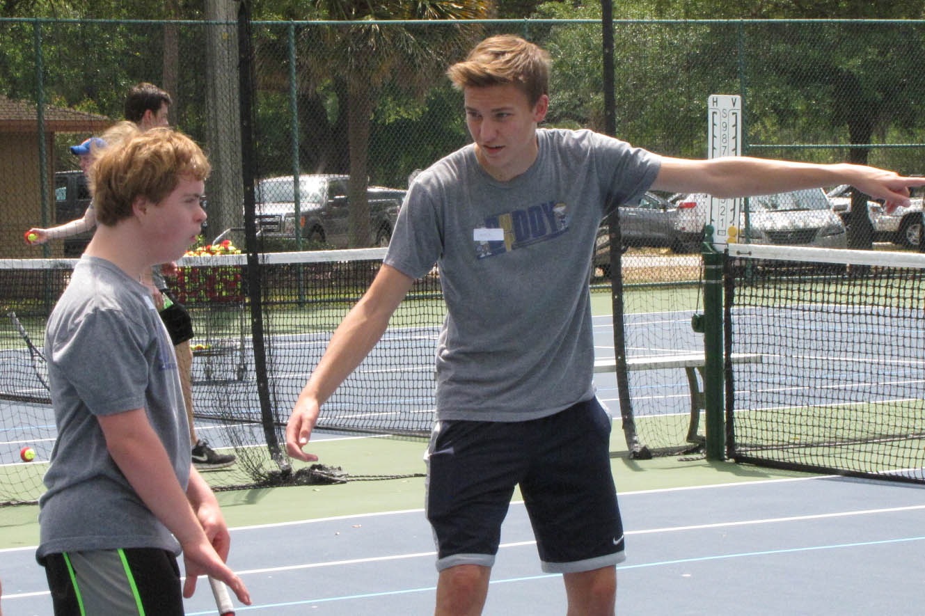 Ferrari coaches one of the kids he works with in the Buddy Up tennis program.