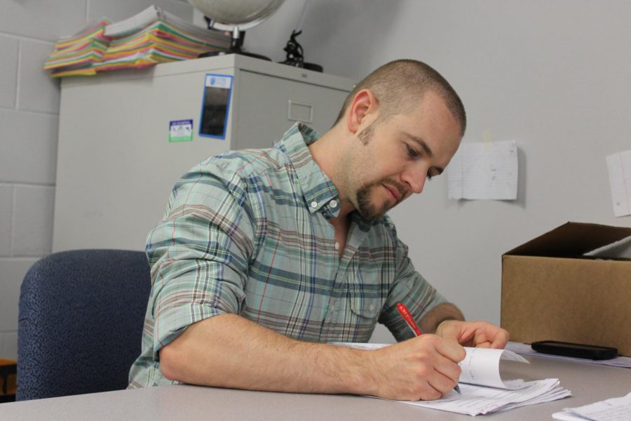Marc Pooler quietly grades papers at his desk. His hard work and outgoing personality led to his win.