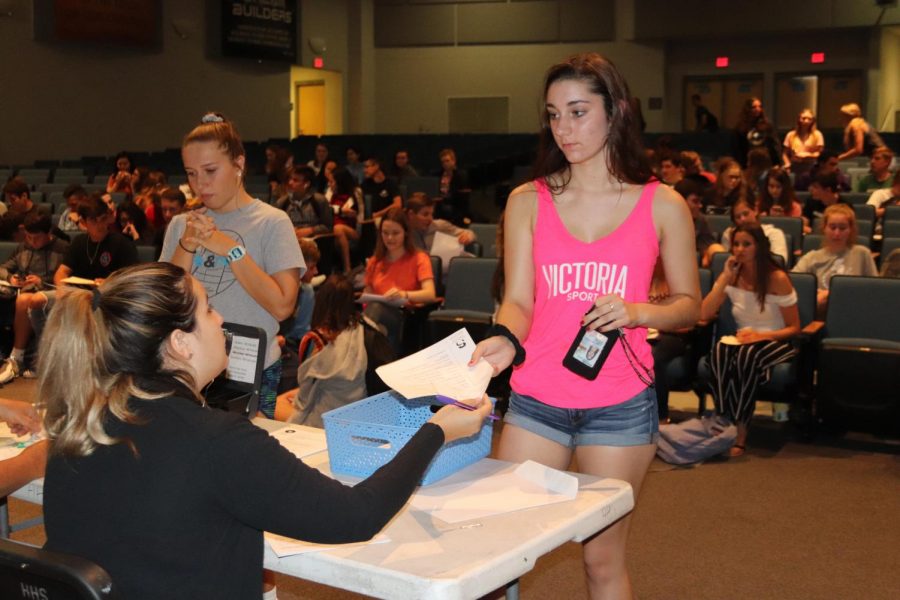 Sophomores Victoria Hayward and Elaina Butler buy their parking passes in the auditorium.