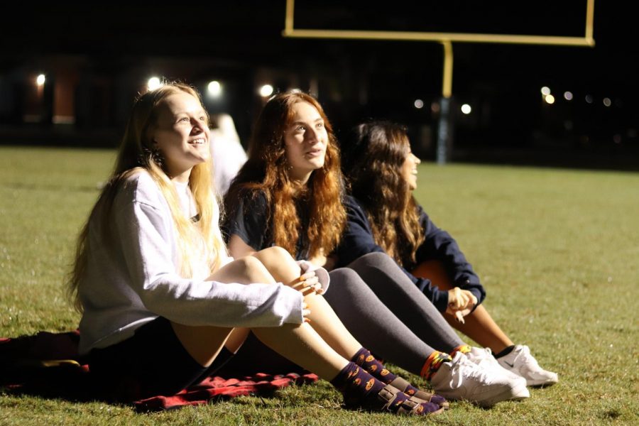 Seniors Faith Hammock, Julia Johnson and Skyler Diserafino wait for the sunrise. They all met up together on the football field with other seniors.