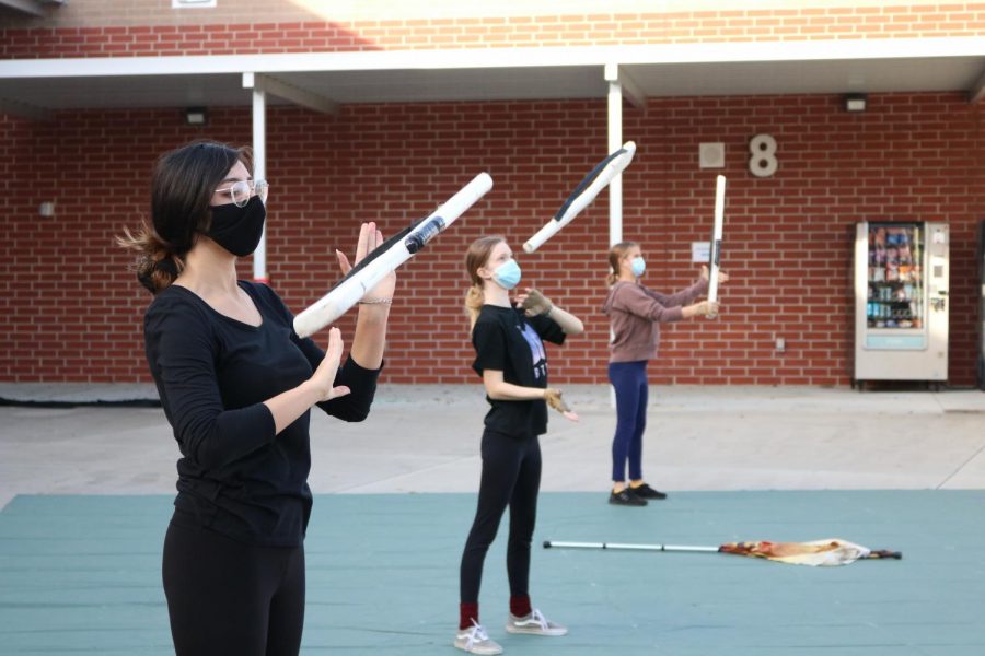Working on their rifle toss on a Thursday afternoon practice, junior Hannah Makhecha, senior Kayden Howell and junior Brooke Karten practice the rifle routine.