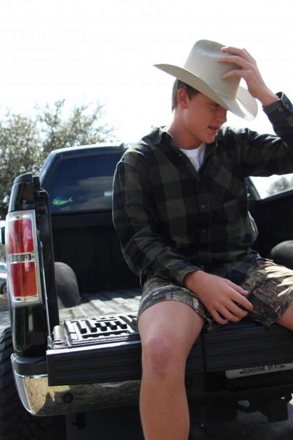 Junior Blake Grose admires his truck as he sits on the back of his tailgate. Grose takes pride in his country lifestyle and could not imagine any other kind of life.