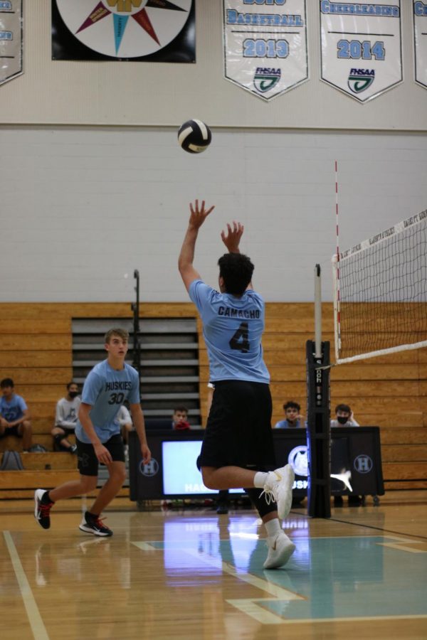 setter Brian Camacho is setting the ball to middle hitter Caden Douglass. 