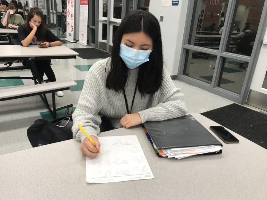 Junior Nina Honda does her precalculus homework in the cafeteria during the pep rally. According to Honda, she decided not to go to another pep rally after her last one was stressful and overwhelming.