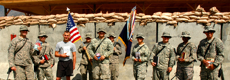 Military members pose for a photo with books sent by Operation Paperback volunteers. In addition to sending normal shipments, the charity also does special projects such as multiple copies of books for military book clubs, and bookshelves full of professional development books for active-duty units.