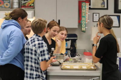 President Annabella Musumeci talks to a group of new club members while they are preparing their chocolate chip cookies. Musumeci was helping students portion out the cookie batter for the correct recipe measures.