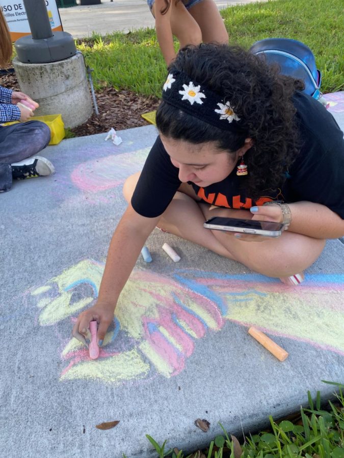 Sophomore Ana Lawrence draws two hands holding each other to show people helping others in need. The members of National Art Honor Society drew this along with other things to spread suicide awareness outside the Seminole County Health Department. 