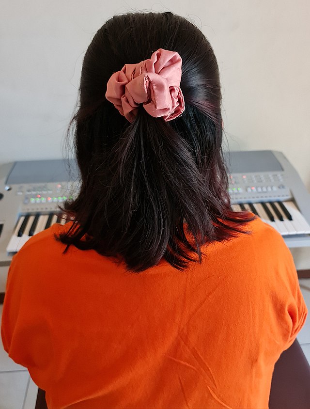 A girl wears a scrunchie to tie up her hair.