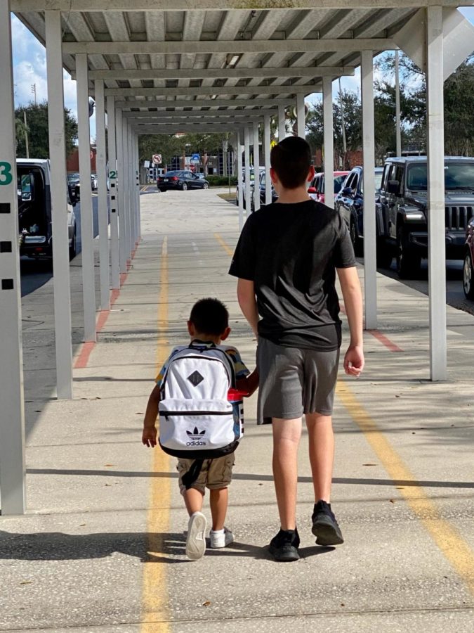 Freshman Aidan Carl walks a pre-K student to his vehicle. Most Hagerty volunteers help at Carillon from 2:30 to 3:30 and help students with assignments and clean up.