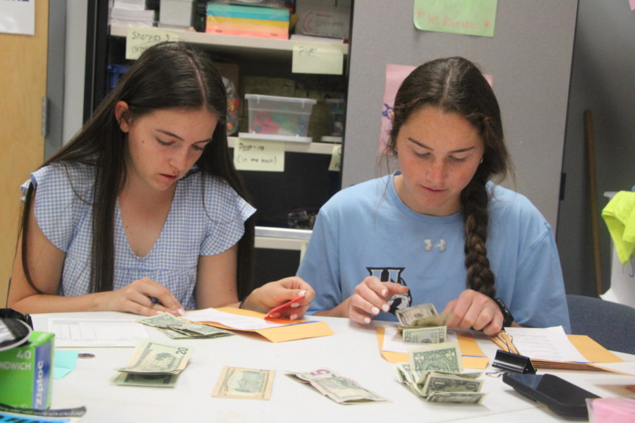 Juniors Ainsley Pomp and Megan ODonnell organize the money received from DARE Week. The money will go to the Nusbaums, who suffered a car accident in December. 