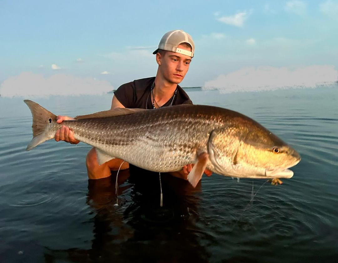 Junior Preston Hearn poses with a large Red fish. Before any sucessful catch, Hearn carefully analyzing the fishs movements and find the best time to strike.