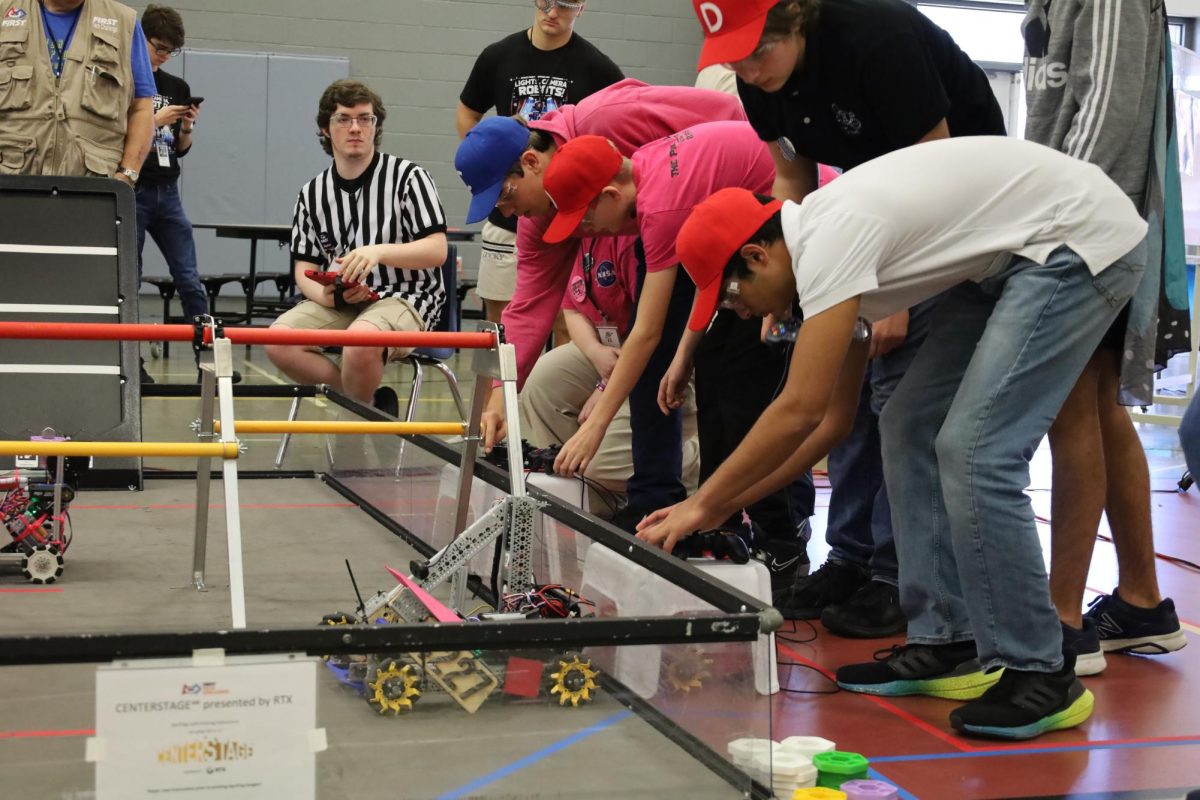 Sophomore Ved Mahesh places team 4772’s robot on the playing field. Each match was two minutes and 30 seconds long, with the first 30 seconds called the autonomous period, where robots had to move around with no input from a driver.