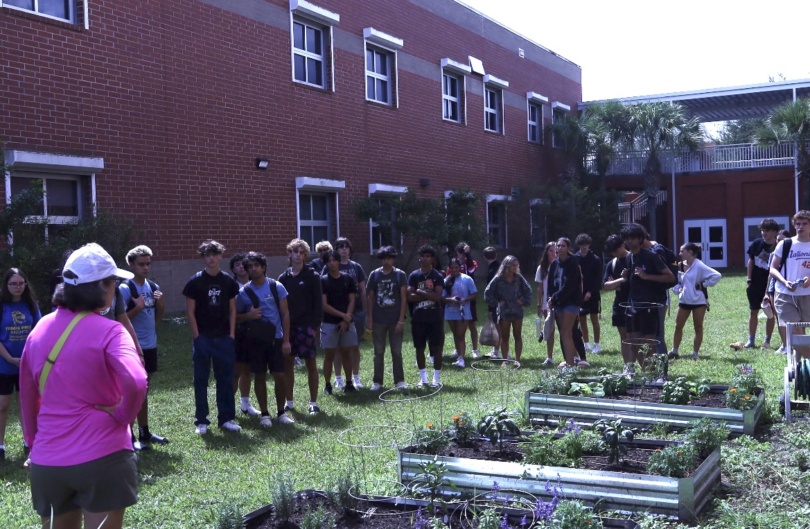 Sponsor Carol Dean shows club members around the garden. Environmental Club has extensive plans for improvements to the area. 