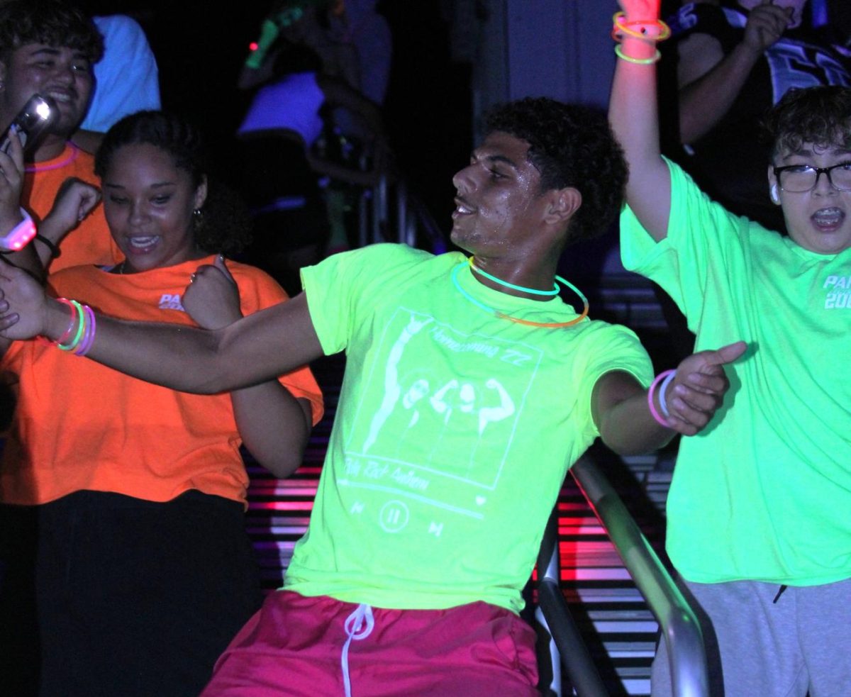 Junior Akrum Baker dances during the glow rally. Leadership students threw glow accessories to the crowd early in the event.