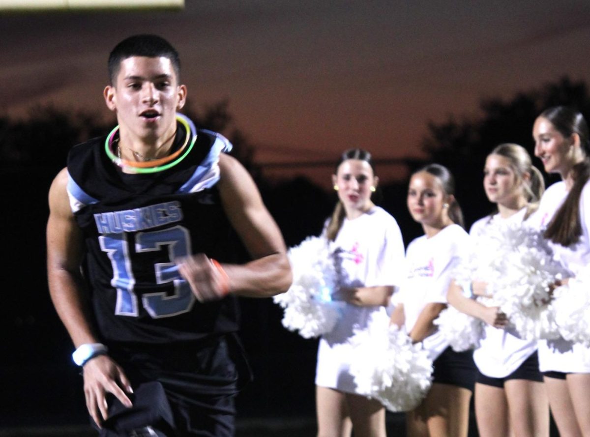 Senior Christian Lopez runs onto the field during Thursday's glow rally. All the senior football players were introduced during the rally.