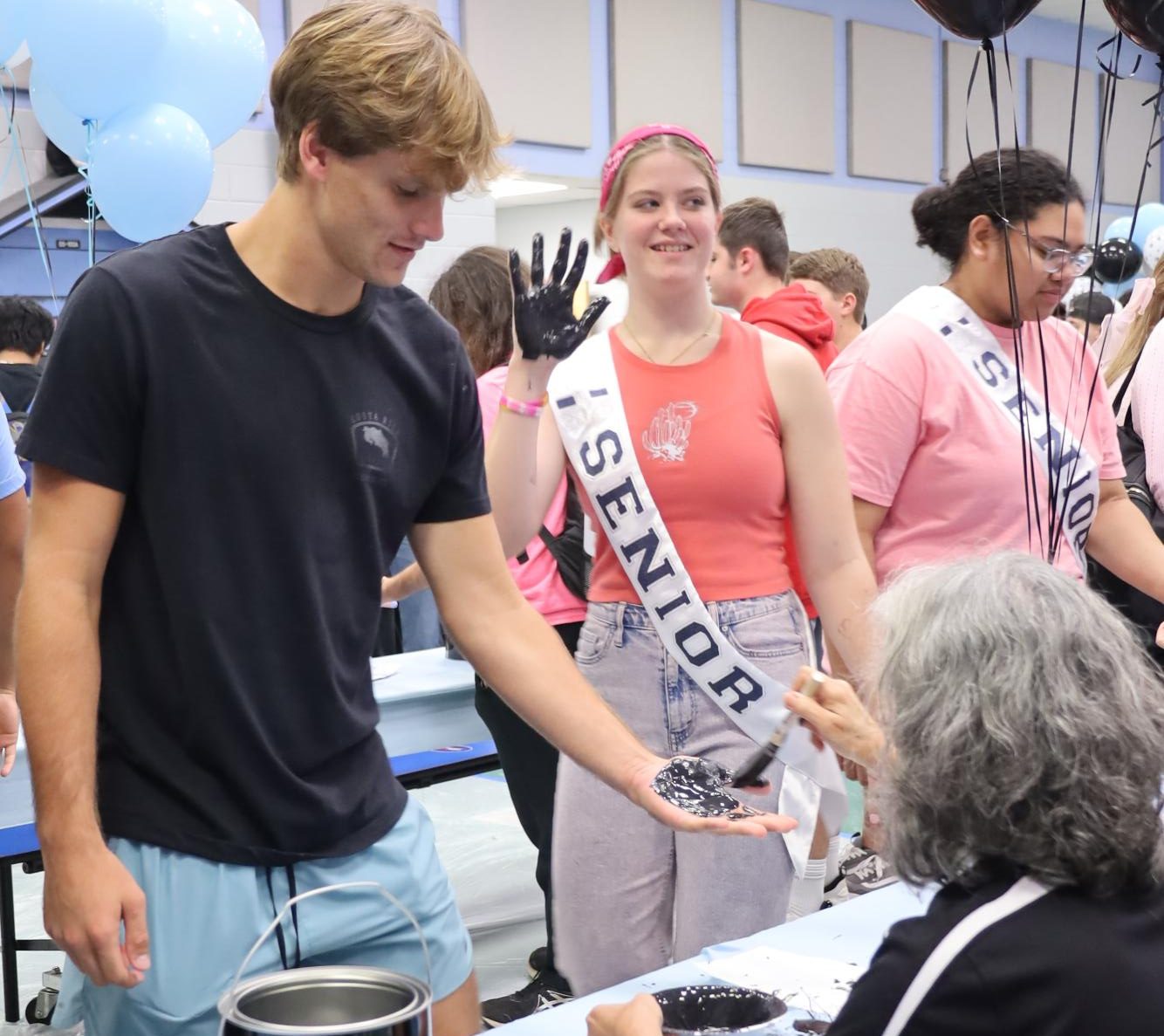 Lining up for hand paint, seniors Caden Mitchell and Alyssa Basillo prepare to put their handprints on the wall for Paws on the Wall. The event was moved to homecoming week after several years of getting scheduled during the Club Crawl at the end of summer.