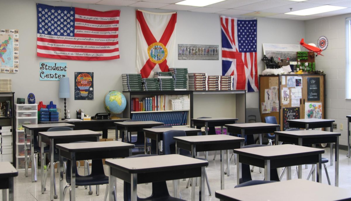 Different flags sit in the back of Amy Bingham's class beside student work on the right. On the left is the American flag with the constitution on the stripes, the middle is Florida's flag and the right is a split between the American and British flag. 