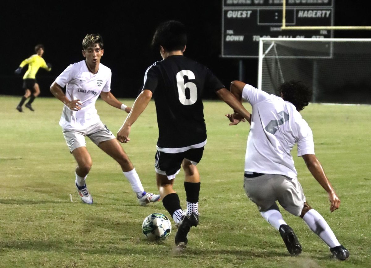 Adrian Davilla dribbles the ball between two players. The game ended in a 4-0 blowout.