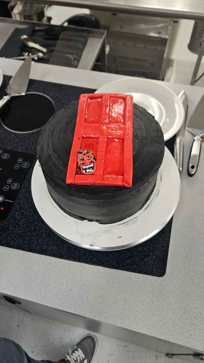 The Insidious cake made in fourth period has a simple design with black frosting and red fondant. The molding of the fondant into the door and devil from the film recreated the chilling horror film.