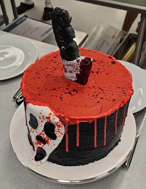 The Scream cake made in fourth period amazes judges with a fondant knife sticking out of the cake's exterior and a detailed Ghostface mask also made of fondant.