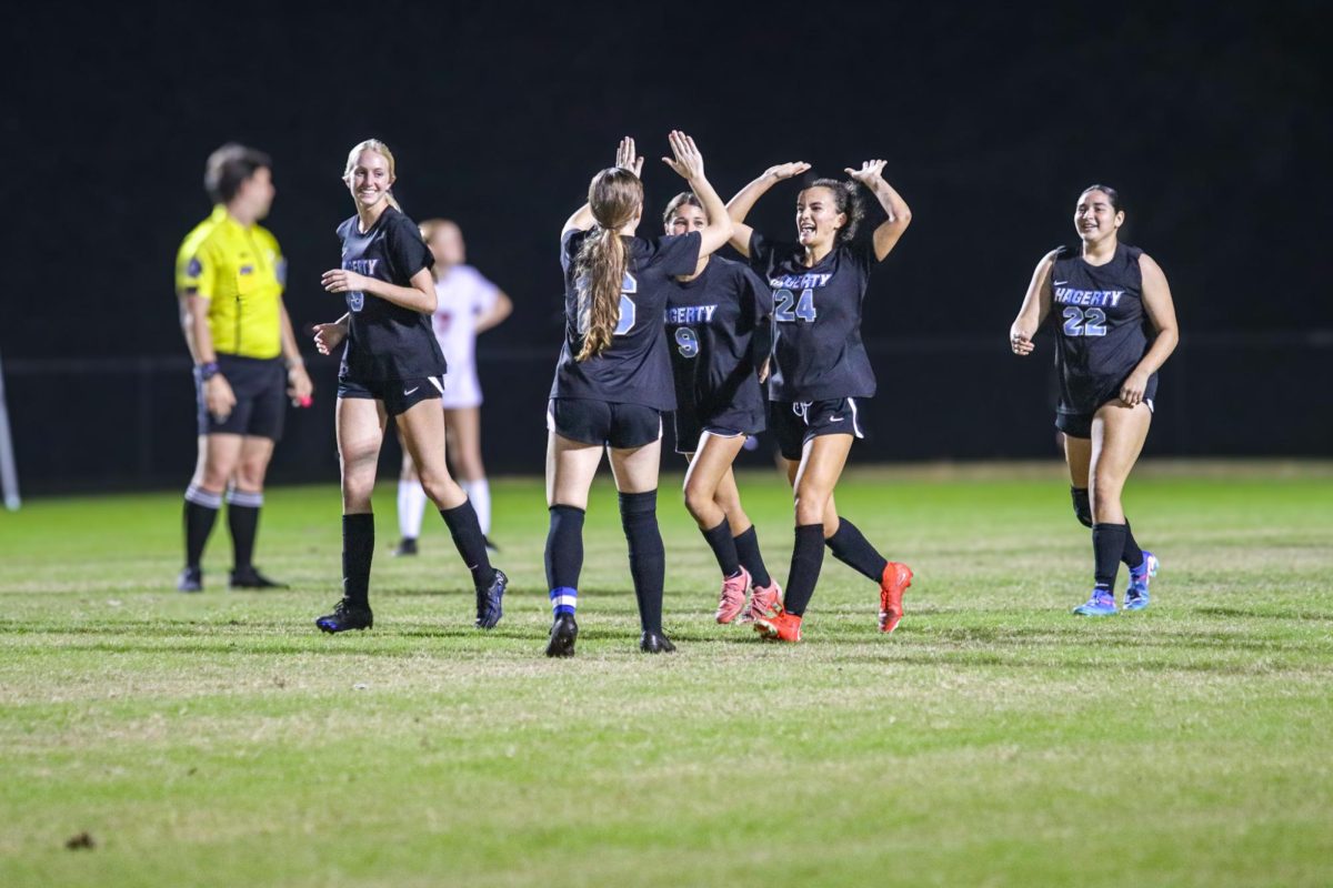 Senior Katherine Smith high fives her teammates during their 8-0 senior night game against East River. The team was also celebrating their senior night during the game, making the win all the better.