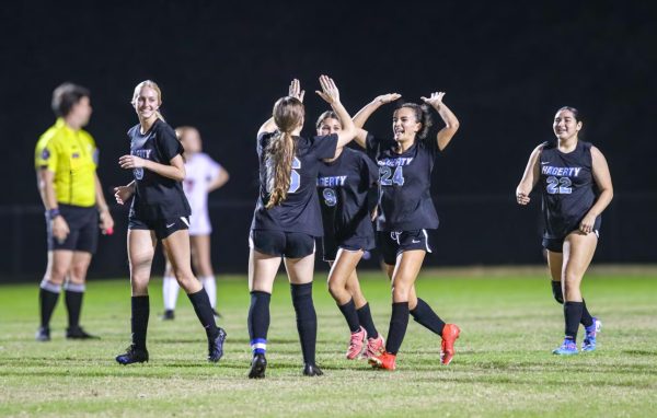 Senior Katherine Smith high fives her teammates during their 8-0 senior night game against East River. The team was also celebrating their senior night during the game, making the win all the better.