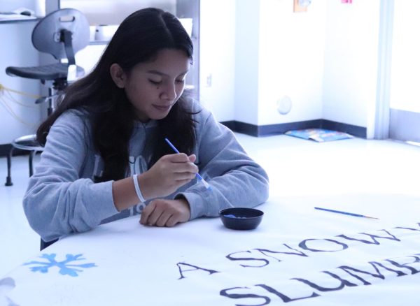 Painting a sign during midblock Leadership class, freshman Amelie Hing preps for Winter Week. Leadership has planned activities for each day, including Flick on the 50, a former homecoming activity that was moved to Winter Week this year.