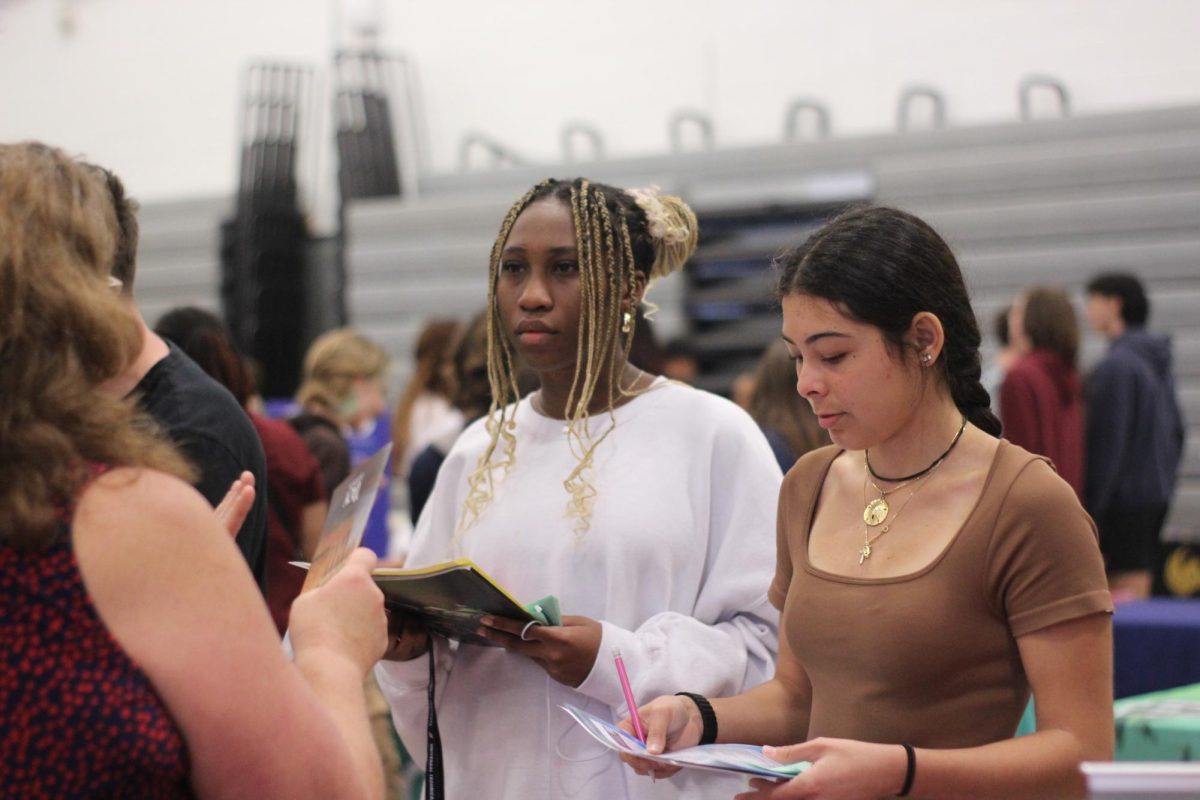 Junior Athena Turner talks to college recruiter about possible majors. Recruiters were standing at each booth, handing out pamphlets for students to learn more about their university. Photo by Carly Elassal