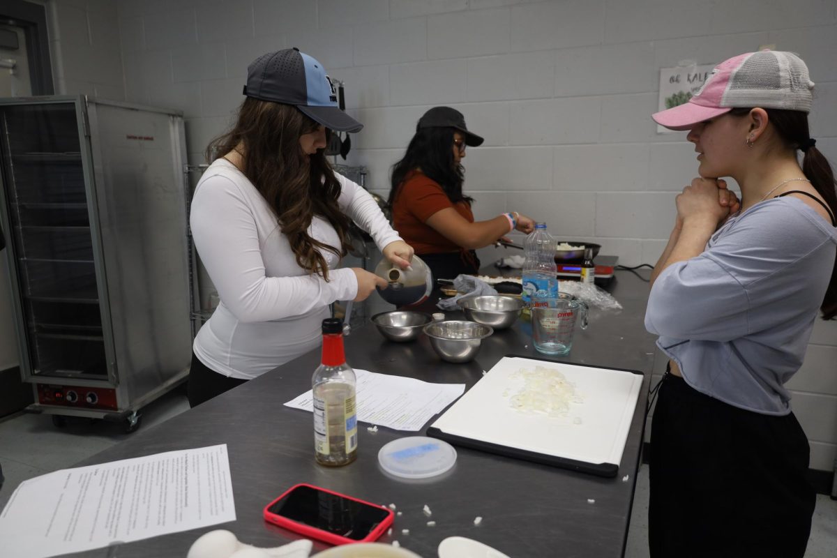 Sophomores Sohni Ali (back left), Mia Lorello (front left) and Aurelia Salisbury (right) make butter fried rice. The students often take place in competitions where they practice industry standard culinary skills. 