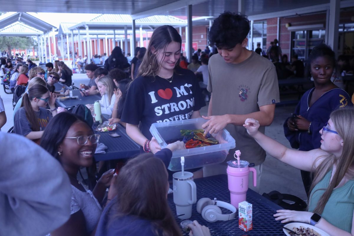 Thursday: "I ♥ Day." Junior Kaden De La Rosa reaches for a pair of sunglasses from senior Celine Merlin. Merlin handed out heart-shaped glasses to students wearing "I ♥ shirts" during second lunch. 